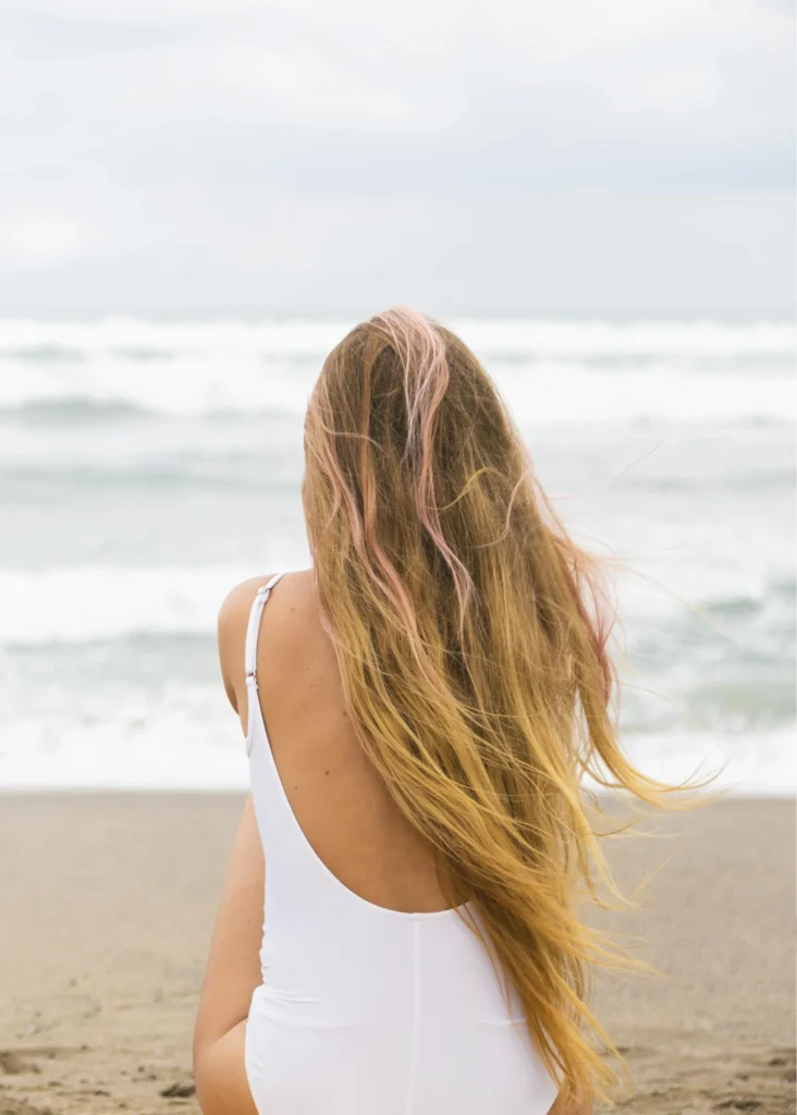 Kobieta z długimi włosami siedzi na plaży